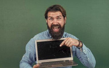 Sakallı ve bıyıklı bir adam üniversitede ya da okulda iş adamı ya da öğretmen gibi görünüyor.