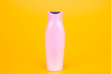 Sarı arka planda beyaz şampuan şişesi, cilt bakımı