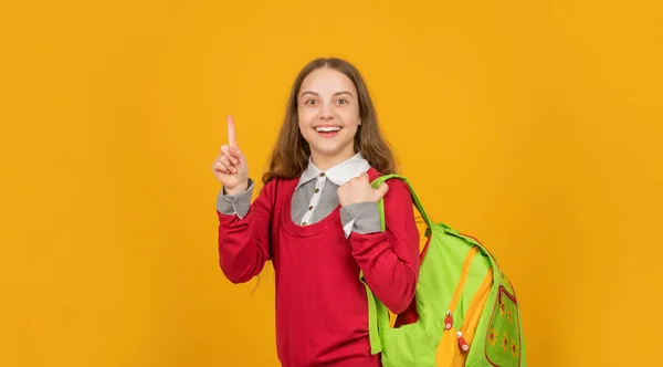 Šťastný inspirován nápadem teen dívka se školním batohem na žlutém pozadí, škola — Stock fotografie