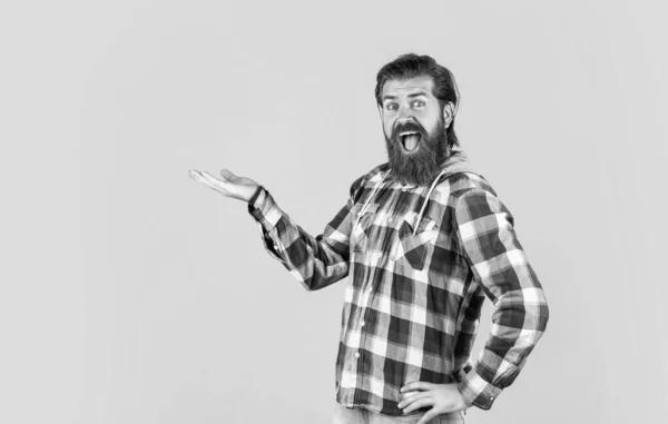 Mature handsome man in checkered shirt has beard on face, presenting product — Stockfoto