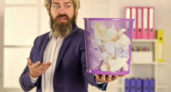 businessman hold full paper bin with crumpled papers. business and trash. man search crimpled paper in basket. ceo in messy office. throw garbage into paper container. selective focus