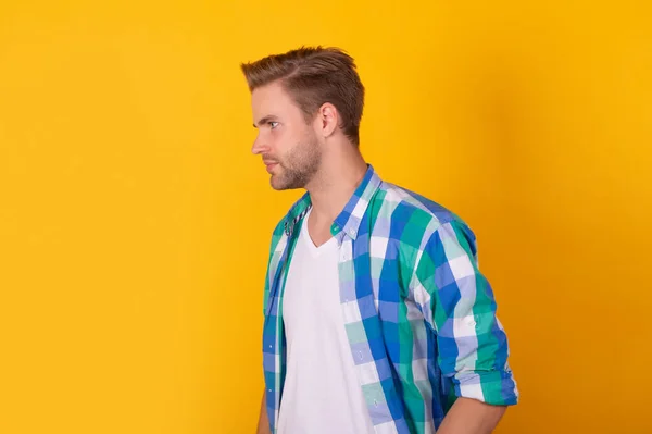 Serious man portrait standing sideway in checked shirt yellow background, profile — стоковое фото