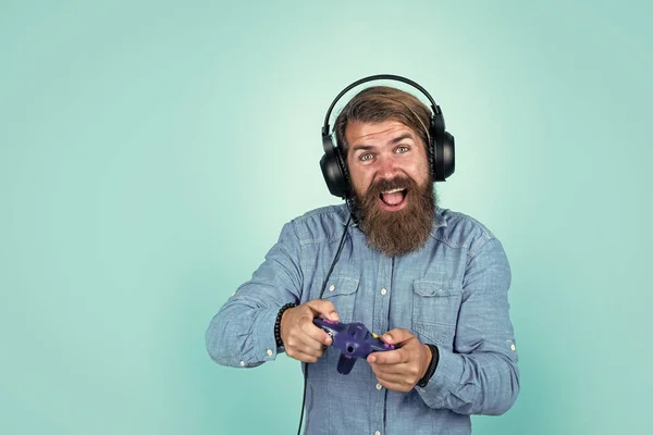 Hipster caucásico con barba y pelo elegante en auriculares con consola de juegos, la vida moderna —  Fotos de Stock