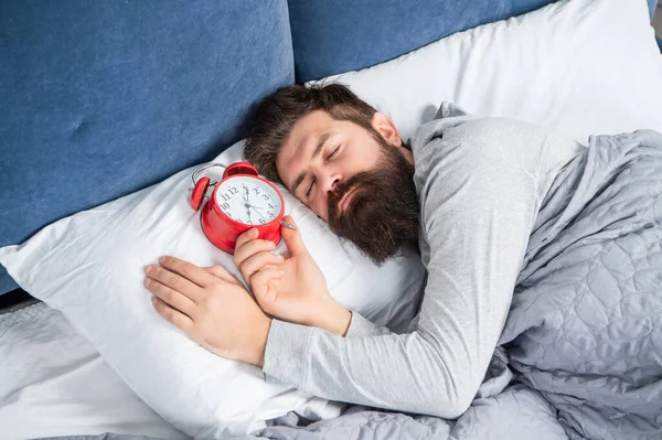 Pria mengantuk dengan jam alarm berada di tempat tidur, waktu tidur — Stok Foto
