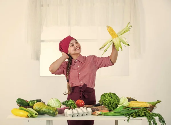 Glad unge med majshuvud i köket, färska grönsaker — Stockfoto