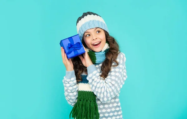 Curious happy child in knitwear hold box. kid with present. teen girl on blue background. — стоковое фото
