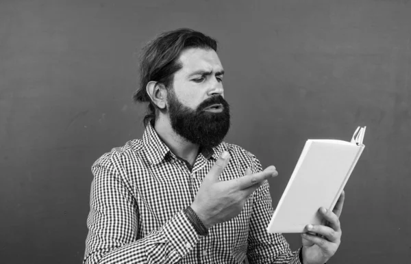 Sakallı ve bıyıklı bir adam üniversitede ya da okulda iş adamı ya da öğretmen gibi görünüyor.