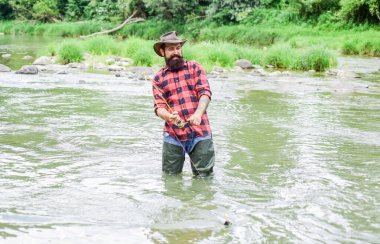 Zalim bir adam nehir suyunda lastik bot giyer. Tatmin olmuş balıkçı. Balıkçı erkek hobisi. Balıkçı ekipmanları. Balık oltaya geldi. Balıkçılık, dikkatli ve tam olarak hazır bulunmanızı gerektirir.
