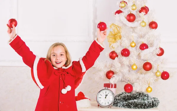 Deixe a criança decorar a árvore de Natal. Parte favorita de decoração. Envolver a criança na decoração. Como decorar a árvore de Natal com a criança. Menina sorridente rosto segurar bolas ornamentos branco interior fundo — Fotografia de Stock