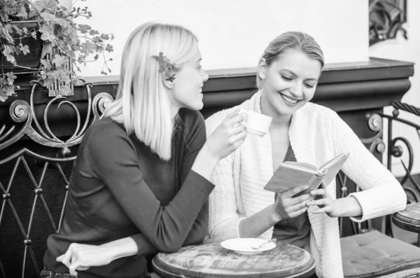 Женская литература. Книга каждая девушка должна читать. Девушки сидят на террасе кафе и пьют кофе. Читаю вдохновляющую книгу. Самосовершенствование и образование. Обсуждение популярной книги бестселлеров — стоковое фото