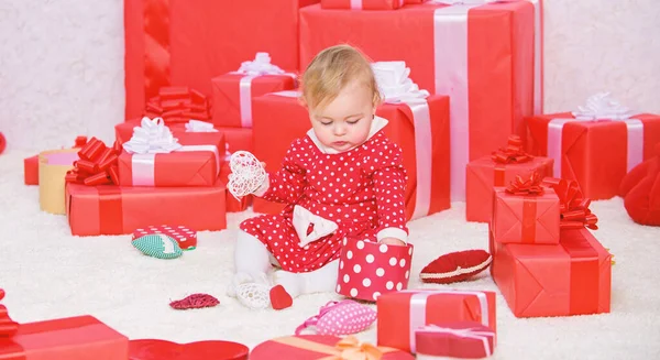 Делиться радостью первого Рождества с семьей. Первое рождество ребенка раз в жизни. Подарки для первого ребенка. Маленький ребенок играет рядом с кучей упакованных красных подарочных коробок. Моё первое Рождество — стоковое фото