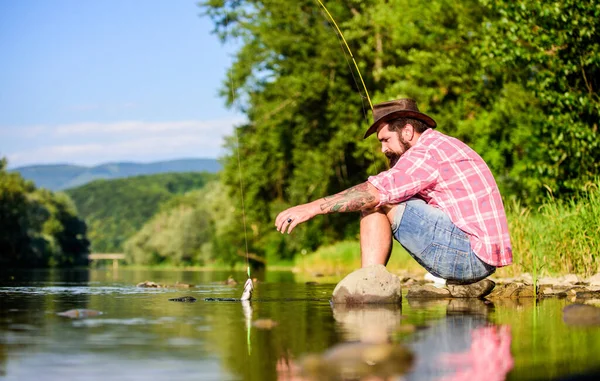 fly fish hobby. Summer activity. mature bearded man with fish on rod. hipster fishing with spoon-bait. The Old Man and the Sea. successful fisherman in lake water. big game fishing. relax on nature