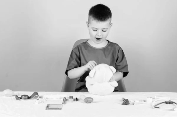 Examen médico. Educación médica. Niño lindo niño futuro médico carrera. Salud. El pequeño doctor está ocupado sentándose en la mesa con herramientas médicas. Concepto de medicina. Procedimientos médicos para oso de peluche — Foto de Stock