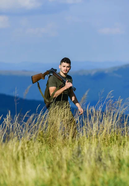 Hunter hold rifle. Nice day for hunt. Hunter spend leisure hunting. Walking in mountains. Hunting masculine hobby concept. Man brutal gamekeeper nature landscape background. Regulation of hunting
