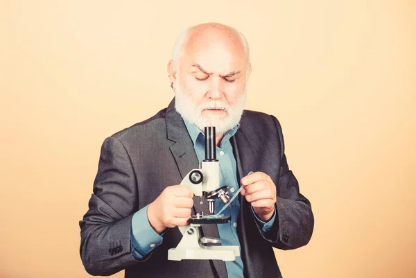 Ώριμο άντρα επίσημο κοστούμι με μικροσκόπιο. Διδακτορική εργασία και μεταδιδακτορική απασχόληση. Διδακτορικά έργα μοριακής βιολογίας. Η βιολογία βίωσε λέκτορα. Καθηγήτρια Πανεπιστημίου. Μικροβιολογία επιστημόνων — Φωτογραφία Αρχείου