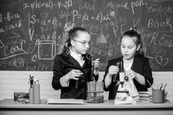 Girls klasskamrater studera kemi. Mikroskop och provrör på bordet. Utföra kemiska reaktioner. Grundläggande kunskaper i kemi. Gör det intressant att studera kemi. Pedagogiskt experiment koncept — Stockfoto