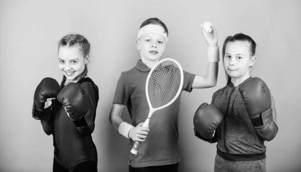 Modi per aiutare i bambini a trovare lo sport che amano. Amici pronti per l'allenamento sportivo. Fratelli sportivi. Il bambino potrebbe eccellere in sport completamente diversi. Ragazze bambini con attrezzature sportive di boxe e giocatore di tennis ragazzo — Foto Stock