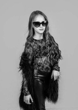 Saf güzellik. Güneş gözlüklü mutlu genç kız. Bahar çocuğu modası. Kıvırcık saçlı çocuk moda kıyafetler giyiyor. Güzellik kavramı. çocukluk mutluluğu. Güzellik ve moda. kadın aksesuar