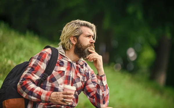 Inspired handsome hipster. Drink tea or coffee. Man with cup outdoors. Enjoying nature at riverside. Guy with backpack relaxing. Inspiration. Man outdoors with cup of coffee. Drinking hot coffee — Stock Photo, Image