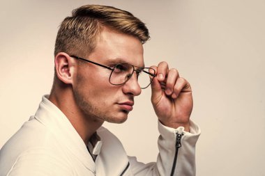 Giymek istediğin moda gözlüğü. Ciddi bir adam beyaz bardakları tamir ediyor. Moda gözlükler. Vizyon düzeltmesi. Düzeltici lensler. Optik göz taraması ve göz doktoru. Yüzün için gözlük.