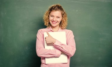 Okula dönelim. Okul eğitimi konsepti. Bayan sevimli öğretmen dizüstü bilgisayarını tahtaya yakın tutuyor. Öğretmenler için yazılım. Modern eğitim. Okul hocası konuyu açıklıyor. Bilgilendirme öğretiliyor