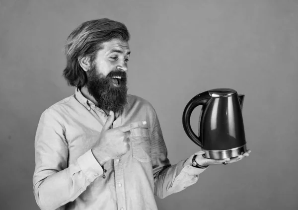 look here. bearded man shop assistant presenting kitchen utensil. useful in housekeeping. mature charismatic male use electric kettle. guy with beard and moustache make tea. drink hot tea