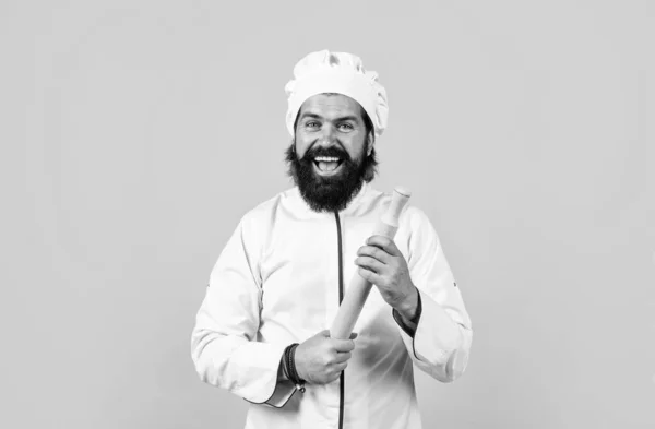 Впевнений шеф-кухар з бородою та вусами у формі кухаря, що тримає штифт на жовтому фоні, щаслива готування — стокове фото