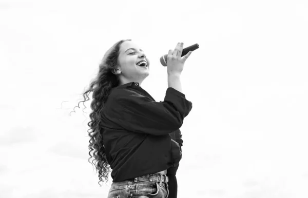Tiener meisje zingen lied in microfoon op lucht achtergrond, muziek — Stockfoto