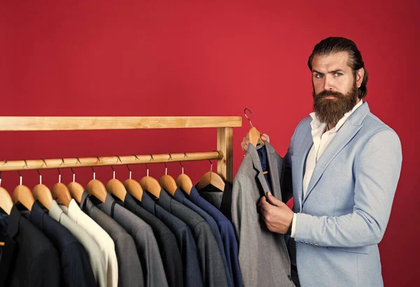 Well groomed man in wedding formalwear has beard choose jacket in wardrobe, atelier — Stock Photo, Image