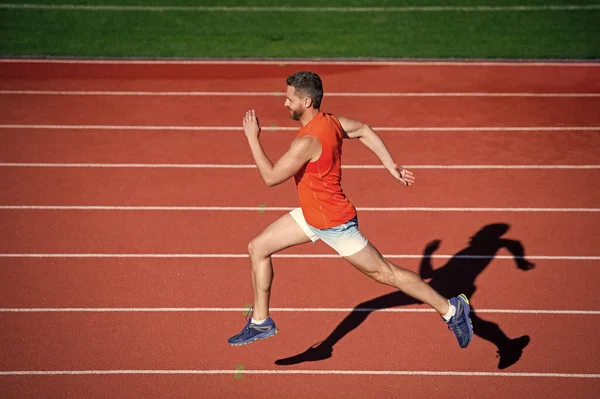 Atlético muscular masculino corriendo en pista de carreras en el estadio al aire libre, objetivo — Foto de Stock