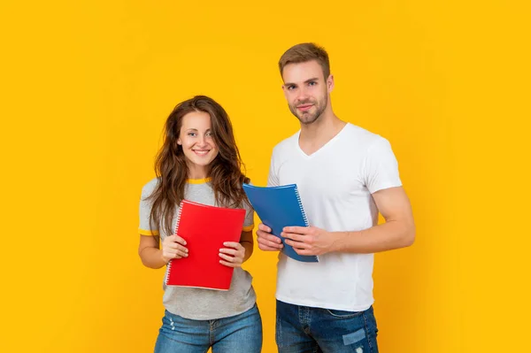 Happy girl and guy in headphones with workbook on yellow background, education — Stock Photo, Image