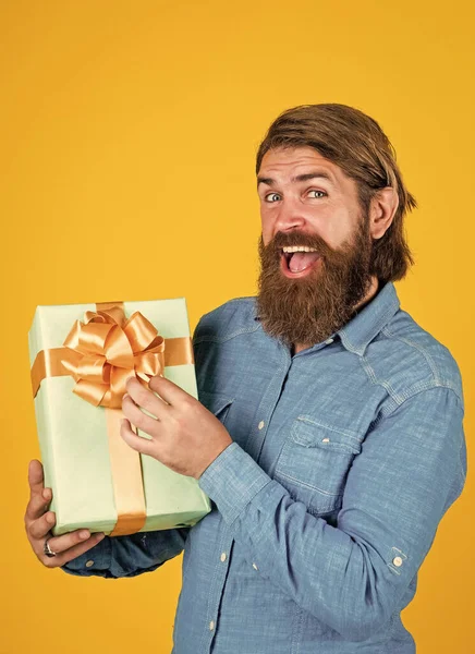 Зрілий чоловік з бородою і модною зачіскою тримає подарункову коробку, сюрприз — стокове фото