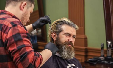 Erkek olmak güzel. Formunu koru. Sakallı adam berbere sakal tıraşı oluyor. Bıyık ve sakal. Kuaförde sandalyede oturuyor. Kuaförde olgun bir adam. Saç bakımı ve erkek bakım konsepti