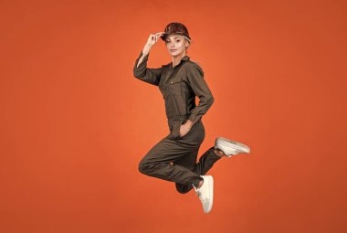 İş üniformalı ve kasklı bir kadın atlıyor. Çalışmak için acele ediyor.