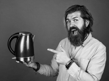 Şuna bir bak. Oda servisinde kullanışlı. Olgun karizmatik erkek elektrikli su ısıtıcısı kullanır. Sakallı ve bıyıklı adam çay yapıyor. Sıcak çay iç. Sakallı adam mağaza asistanı mutfak aletlerini sunar.