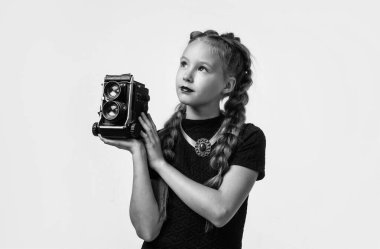 Retro kameralı şık bir çocuk beyaz fotoğraflarla izole edilmiş bir fotoğraf çekiyor.