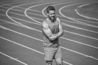 Stadyumda egzersiz yaptıktan sonra sakatlandı. Spor salonu açık havada. Yaralı kaslı atletik adam. Spor eğitimi. Erkek travması. Sporcu sporcu kaslarını esnetir ve eklem yoğurur. Acı hisset