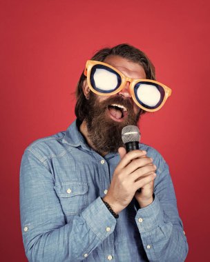 Mikrofonlu komik sakallı adam. Parti gözlüklü vahşi beyaz hippi. Karaoke şarkıcısı. Tıraşsız, uzun saçlı adam. Berber ve kuaför. Erkek mikrofonla şarkı söyler