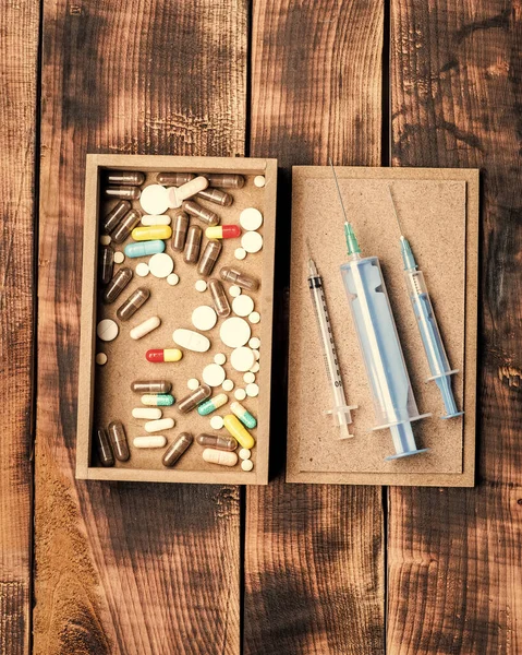 Medicamentos farmacéuticos píldoras y viales de jeringa en caja sobre fondo de madera, botiquín de primeros auxilios — Foto de Stock