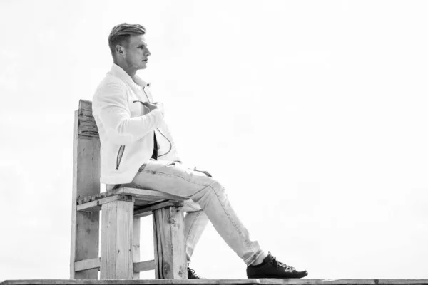 Bello giovane ragazzo in stile casual rilassarsi sulla sedia di legno godendo di aria fresca cielo nuvoloso idilliaco per lo spazio copia, all'aperto — Foto Stock