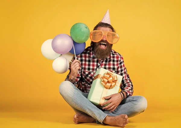 Mutlu, sakallı, sakalsız ve şık saçlı yakışıklı adam. Günlük kıyafetler giyer, hediye tutar, parti balonları, iş ödülü. — Stok fotoğraf