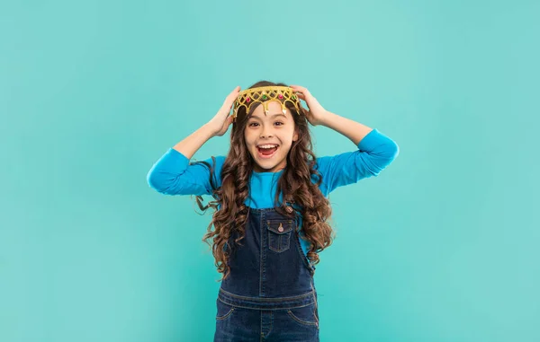 Laughing child with curly hair in queen crown on blue background, happiness — Foto de Stock