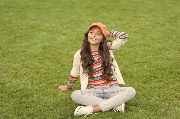 행복 한 여대생 이 푸른 잔디 위에 앉아 미소짓는다 — 스톡 사진
