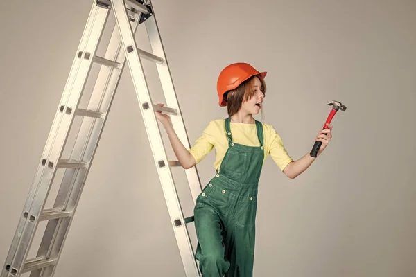 エンジニアティーンは建設労働者です。国際労働者の日。脚立の電気技師だ。ヘルメットの女の子は建築家を演じる。建物を建て直しました。子供の建設だ。自信のある労働者 — ストック写真
