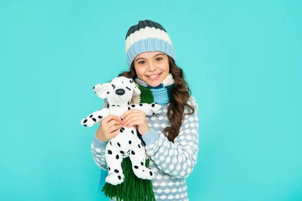 Cheerful child in knitwear hold toy. teen girl on blue background. happy childhood. kid playing toy — Stockfoto