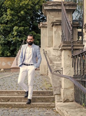 Resmi takım elbiseli, yakışıklı, olgun sakallı bir adam.