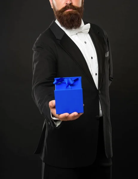 Cropped gentleman in tuxedo bow tie formalwear on black background with gift box. boxing day — Stockfoto