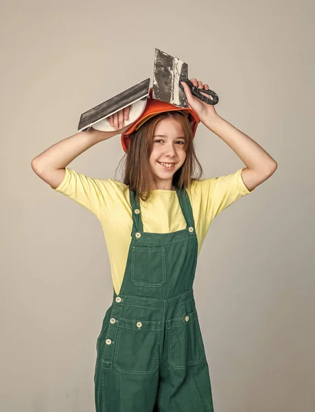 Веселая девушка-подросток в рабочей форме и шлеме лопатки, штукатурка — стоковое фото