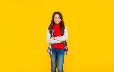 Sarı arka planda sıradan giyinmiş mutlu bir genç kız.