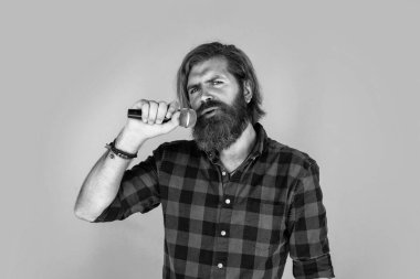 Mikrofonlu duygusal hipster. Mikrofonlu erkek şarkıcı. Karaoke konsepti. Kareli gömlekli sakallı adam şarkı söylüyor. Sıradan bir adam şarkı söylerken insani duygularını ifade eder. Dünyaya uyum getirir.